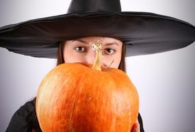 Young witch holding a pumpkin (focus on pumpkin)