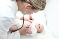 Kinderkrankenschwester mit Stethoskop an Baby