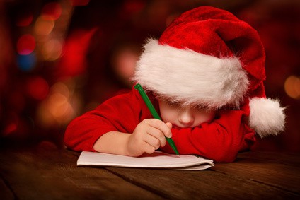 Christmas child writing letter in red Santa hat