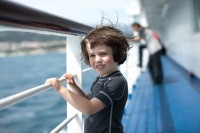 a happy child on ferry boat looking out to sea