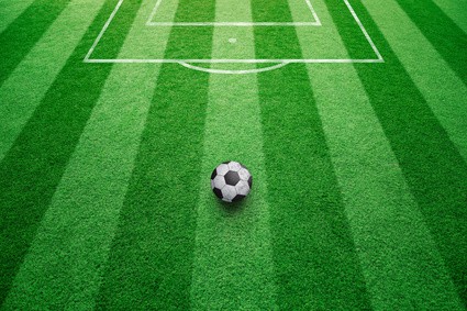 Conceptual soccer free kick ball background. Football ball on sunny soccer field ground.