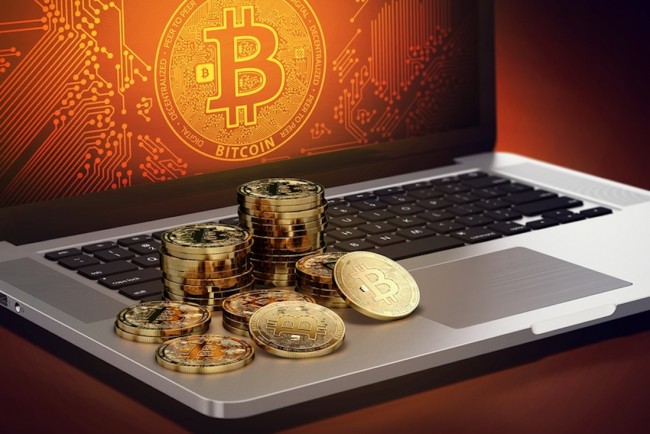 Bitcoin piles laying on computer with Bitcoin logo on-screen. Bitcoin decline concept. 3D rendering