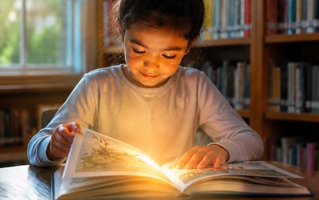 Bambina che legge un libro in biblioteca per la Giornata Internazionale dell’Alfabetizzazione