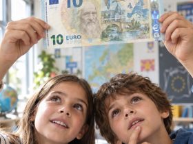 Due bambini osservano in controluce una nuova banconota da 10 euro con Leonardo da Vinci, un fiume e alcuni uccelli.