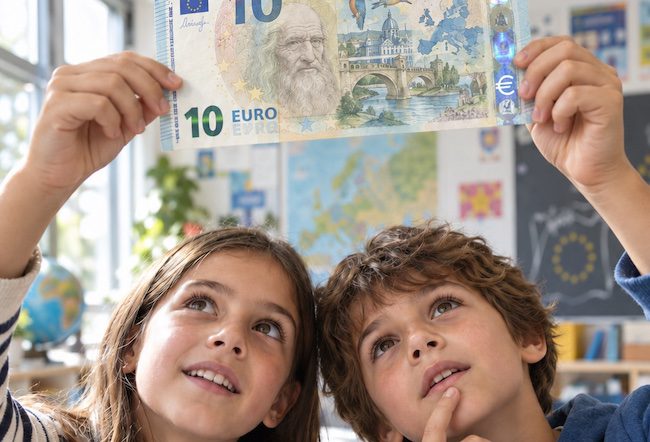 Due bambini osservano in controluce una nuova banconota da 10 euro con Leonardo da Vinci, un fiume e alcuni uccelli.
